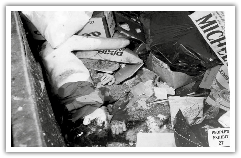 A photo from the crime scene of Audrey Nelson's death. A female body, nude from the waist down, is visible amid trash and empty cardboard boxes.